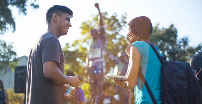 Two students talking in front of the 菠菜网lol正规平台 1968 Olympics Statue.