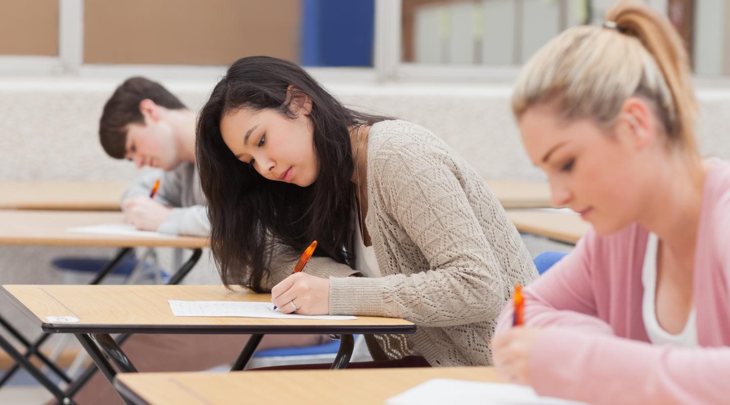 Three students in the classroom taking an exam.