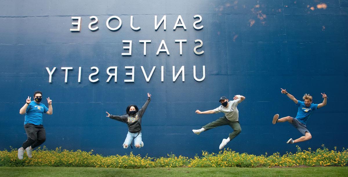 菠菜网lol正规平台 students in masks jumping up in the air.